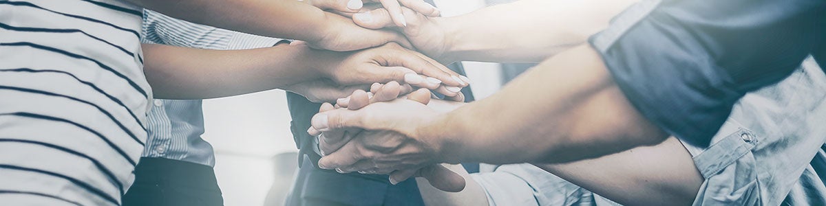 people stacking hands in sign of unity and support
