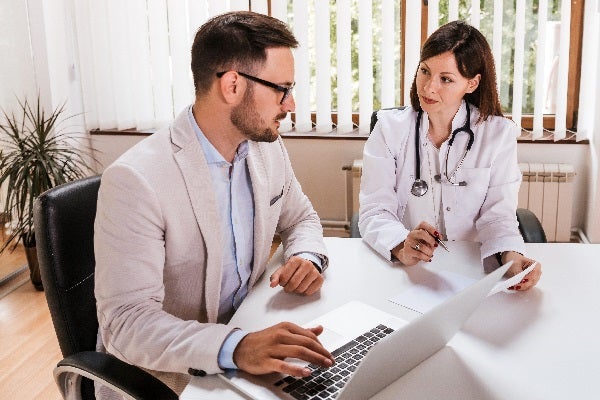 man in business suit talking to female doctor