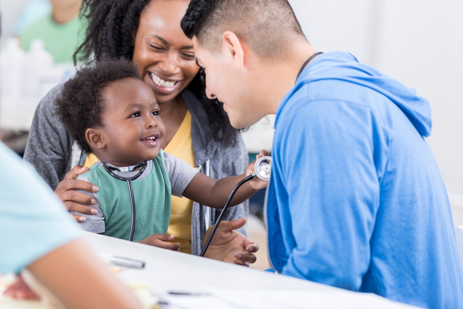male health care worker talking to mother and her child