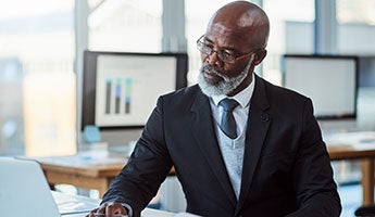 a man in a business suit looking inquisitively at a laptop