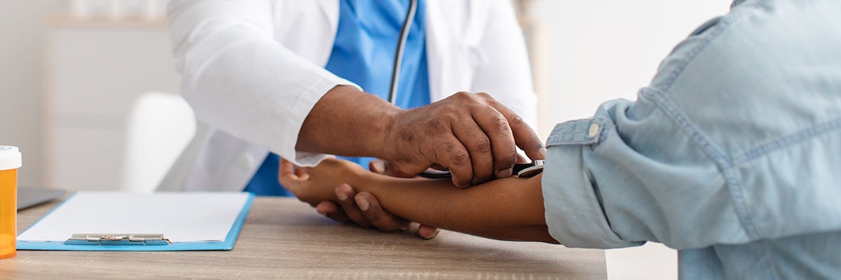 A physician listens to pulse using a stethoscope laid on a patient's forearm
