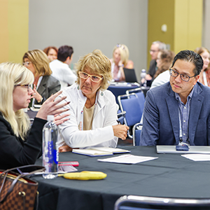 three conference attendees sitting at table having discussion